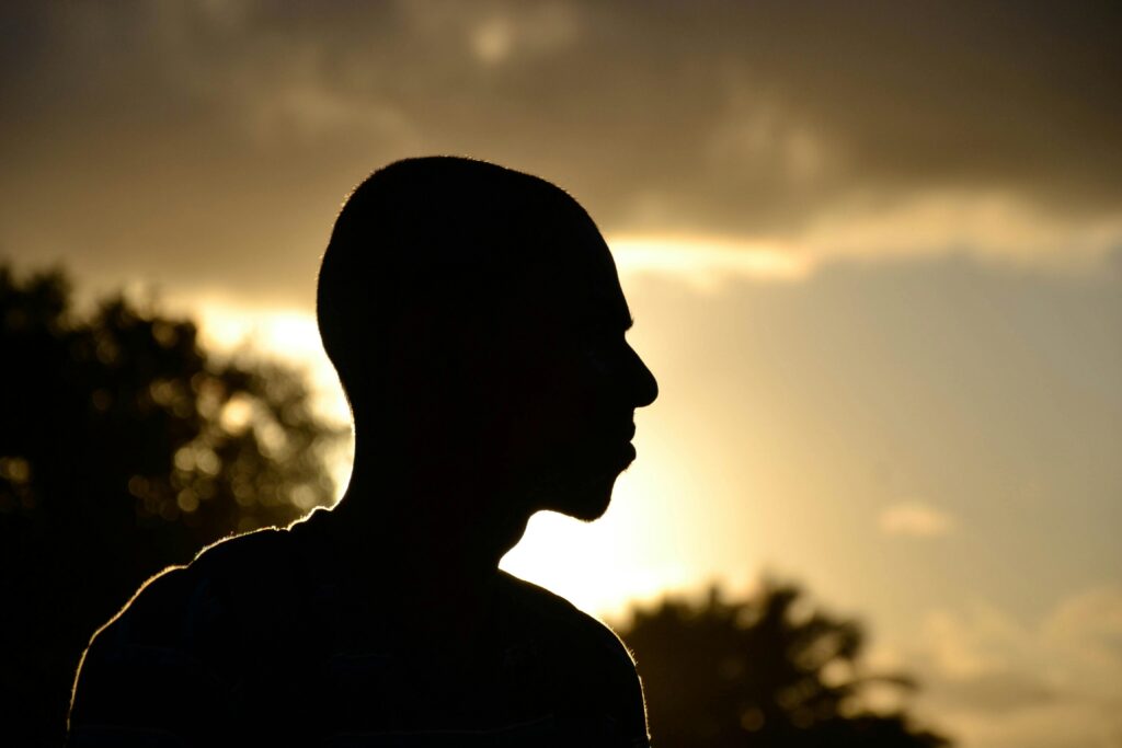 A dramatic silhouette of a person against the evening sky with sunset glow.